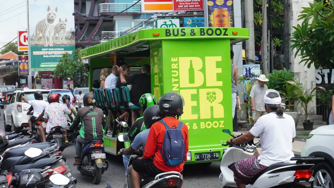 The party bus rolling through busy Kuta traffic surrounded by scooters